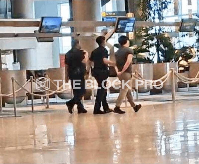 Su Zhu being escorted through Changi airport during his arrest.